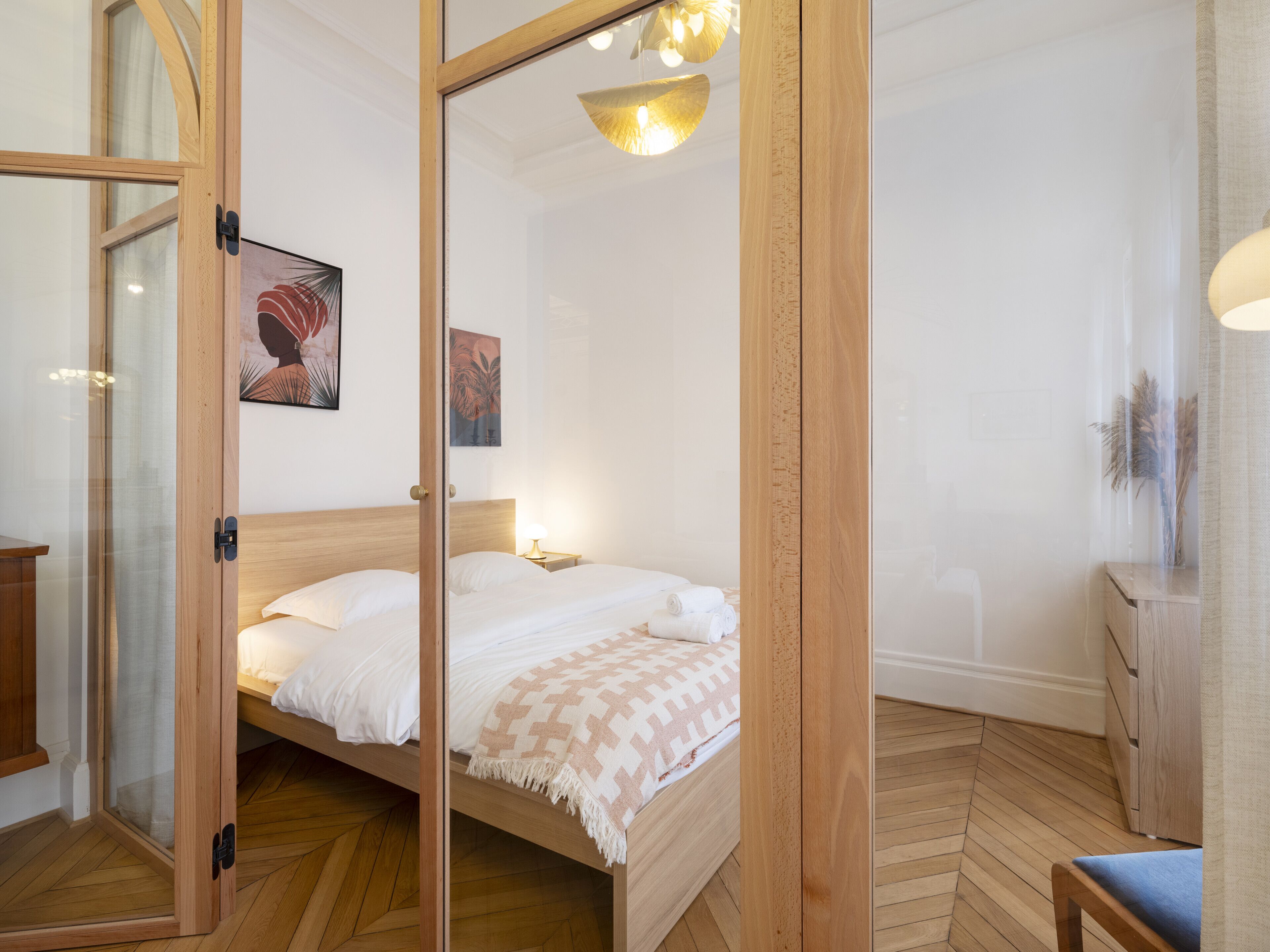 Een slaapkamer met een houten bed, een nachtkastje en een wandlamp.