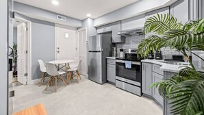 A compact kitchen with a dining area, featuring modern appliances, a white tiled backsplash, and a potted plant. - Cozy Apt in Center City Very Central Location (Philadelphia)