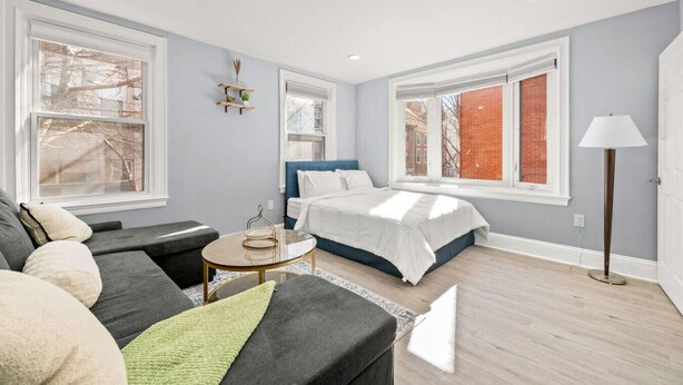 A modern bedroom with a bed, a sofa, a small table, and a lamp. - Cozy Apt in Center City Very Central Location (Philadelphia)