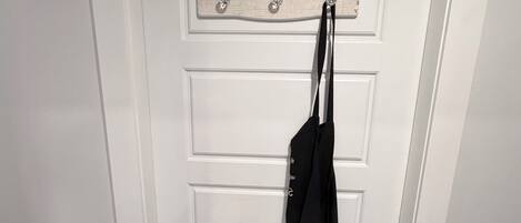 A white door with a sign above it that reads 'LAUNDRY ROOM' and lists steps 'WASH, DRY, FOLD, REPEAT.' A black garment is hanging on a hook to the right of the door.