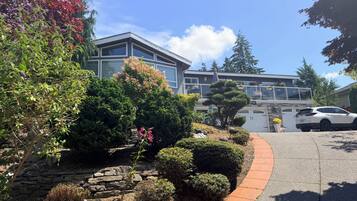 A residential area with a two-story house, a driveway, and a parked car.