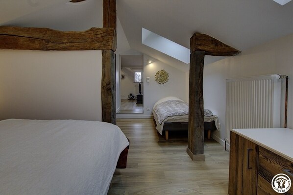 A bedroom with a loft bed, a wooden beam structure, a radiator, and a skylight. - Le Grenier de Bussière (SAINT DIDIER SUR CHALARONNE)
