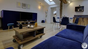 Una sala de estar moderna con un televisor grande, una mesa de centro de madera y un sofá azul.