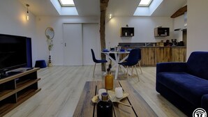 Una sala de estar moderna con televisor, sofá y comedor con sillas y mesa.