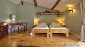 Ein Schlafzimmer mit zwei Holzbett, einem Schreibtisch mit Stuhl, einem Bücherregal und einer Lampe.