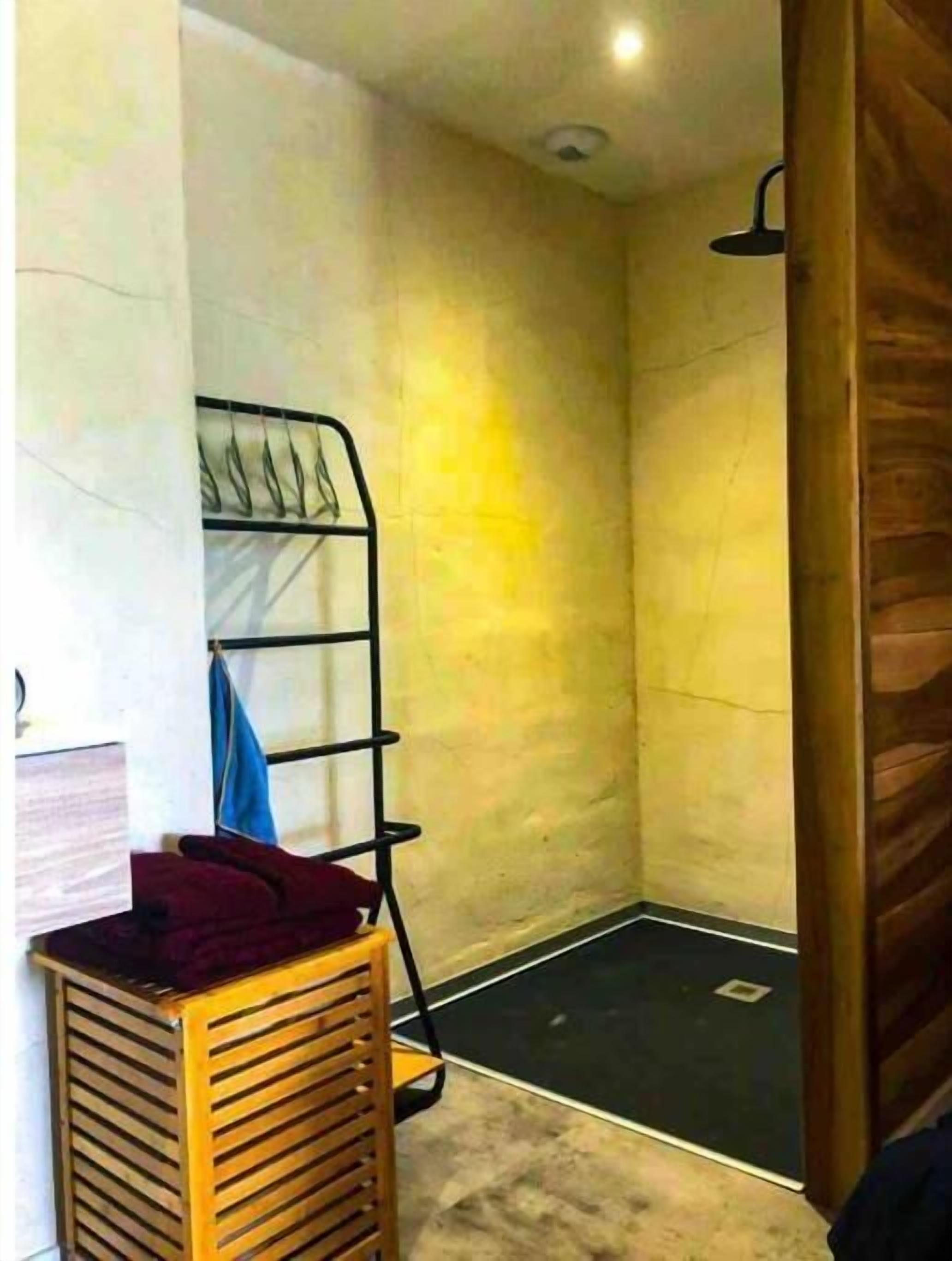 Un petit espace douche fermé, avec un banc en bois et un porte-serviettes.