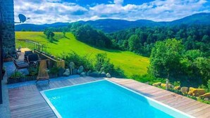 Un espace piscine offrant une vue sur des collines verdoyantes et des montagnes.