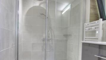 Une salle de bain moderne avec une douche à parois de verre, un évier en acier inoxydable et un plancher en bois.