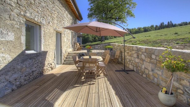 A stone building with a wooden deck, outdoor furniture, and a large umbrella. - la Mine - Saint-martin-du-fresne (SAINT-MARTIN-DU-FRESNE)