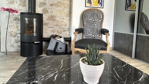 A living room with a stone wall, a black fireplace, a wooden chair, a table with a potted plant, and a painting on the wall. - la Mine - Saint-martin-du-fresne (SAINT-MARTIN-DU-FRESNE)