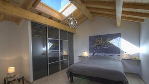 A bedroom with a large bed, a sliding glass door, a skylight, and a painting on the wall. - la Mine - Saint-martin-du-fresne (SAINT-MARTIN-DU-FRESNE)