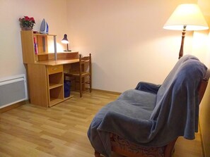 A room with a wooden desk, chair, and a lamp.