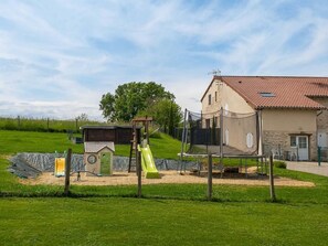 A playground with a slide and swings, a small shed, and a house with a tiled roof.