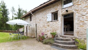 A stone house with a gravel patio, outdoor seating, and potted plants. - Le Tilleul - Courmangoux (COURMANGOUX)