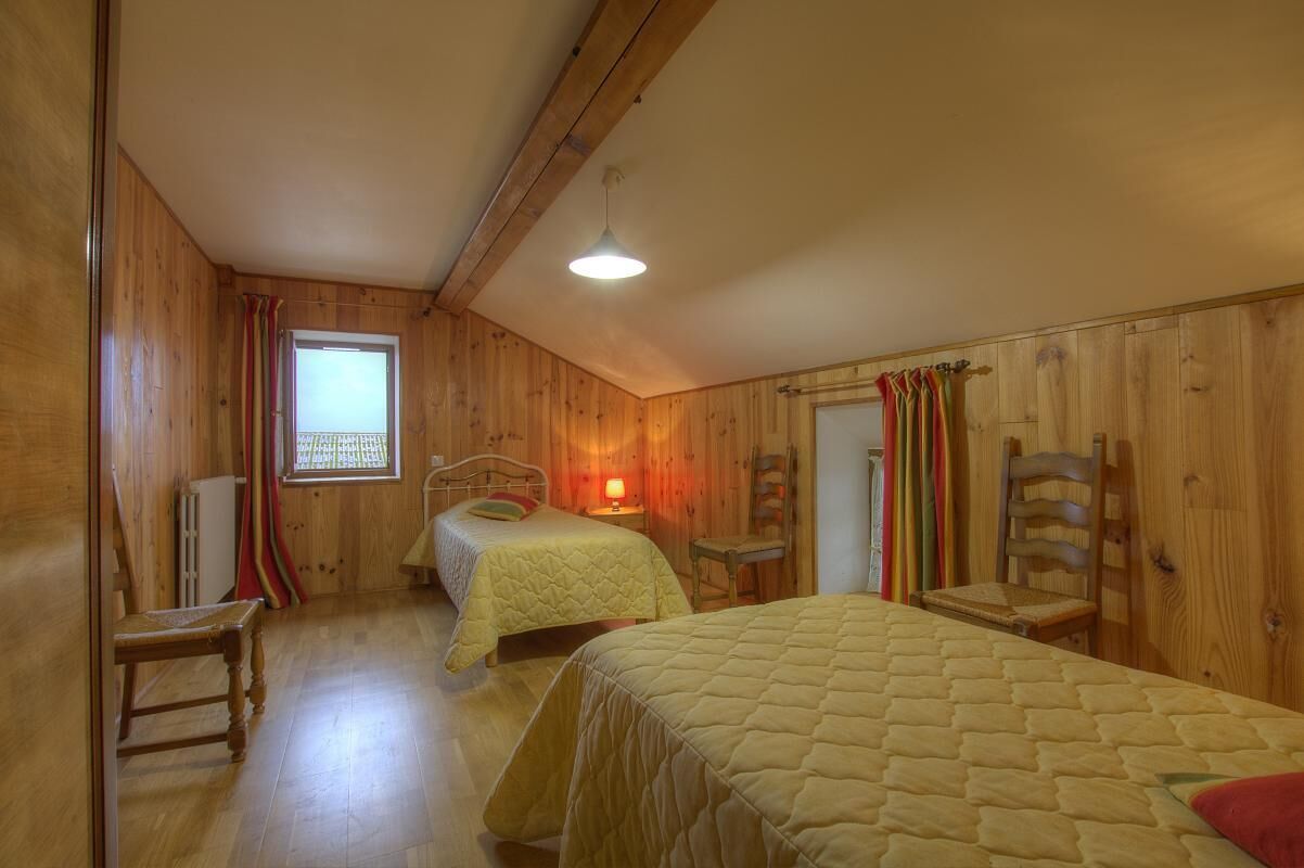 Une pièce en bois avec deux lits, une fenêtre et un radiateur.