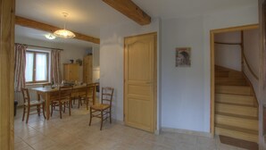 Un espace repas avec une table et des chaises en bois, une porte en bois et un escalier.