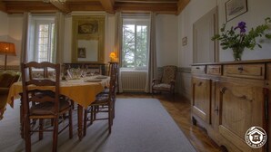 A dining room with a wooden table and chairs, a chandelier, and a cabinet with a vase of flowers.