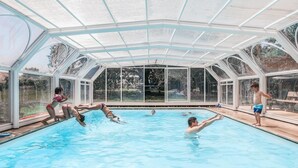 An indoor swimming pool with a glass ceiling, surrounded by a white frame.