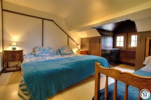 Un dormitorio con una cama, cabecera de madera, mesitas de noche y un aparador.