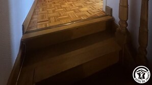 A wooden staircase leading to a room with a herringbone-patterned floor and a wooden door. - G424020 - Tramoyes - Gîte (TRAMOYES)