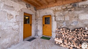 Un intérieur rustique avec deux portes en bois, un mur en pierre et une pile de bois de chauffage.