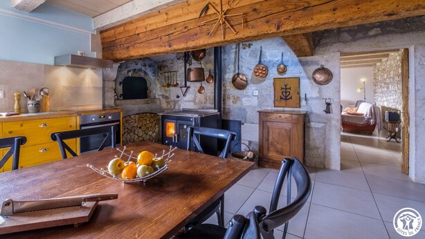 Une cuisine rustique avec un mur en pierre, des poutres en bois et divers ustensiles de cuisine accrochés au mur.