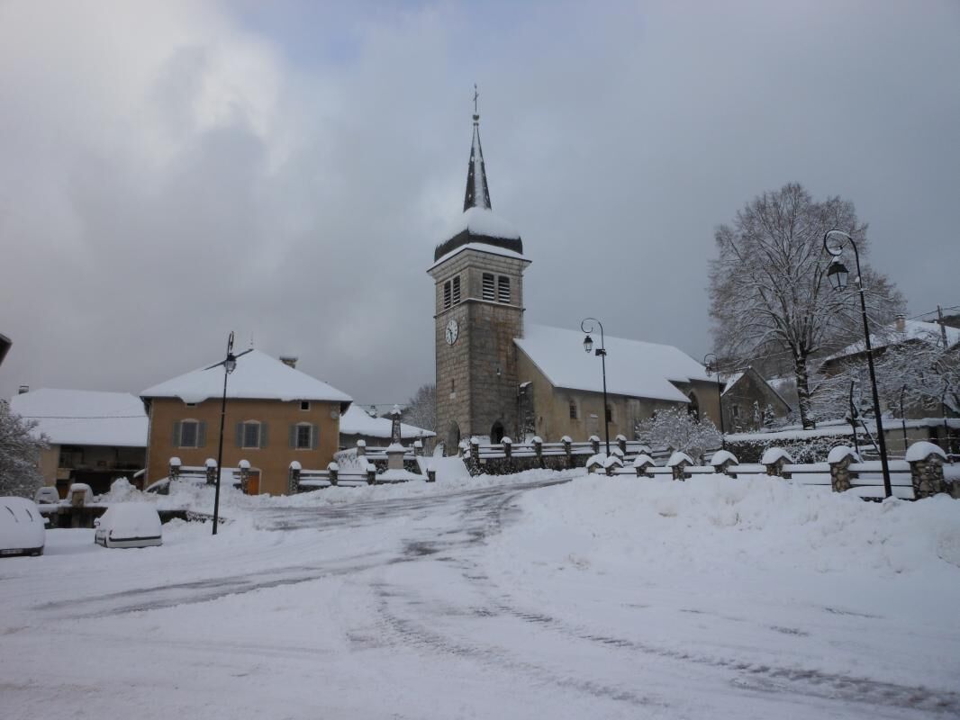 Une rue enneigée bordée d’une église et d’immeubles d’habitation.