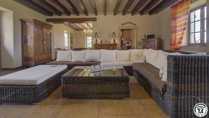 Un amplio salón con un sofá modular grande, una mesa de centro de vidrio y un mueble de madera.