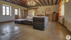 Un salón amplio con techo alto, vigas de madera a la vista y un sofá grande de mimbre.