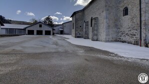 A large, stone building with multiple garage doors and a paved area in front.
