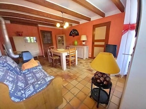 Una sala de estar con un sofá, una mesa de comedor con sillas, una lámpara y una zona de cocina con armarios.