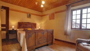 Cozy retreat with a wooden bed, nightstand, and window with curtains.