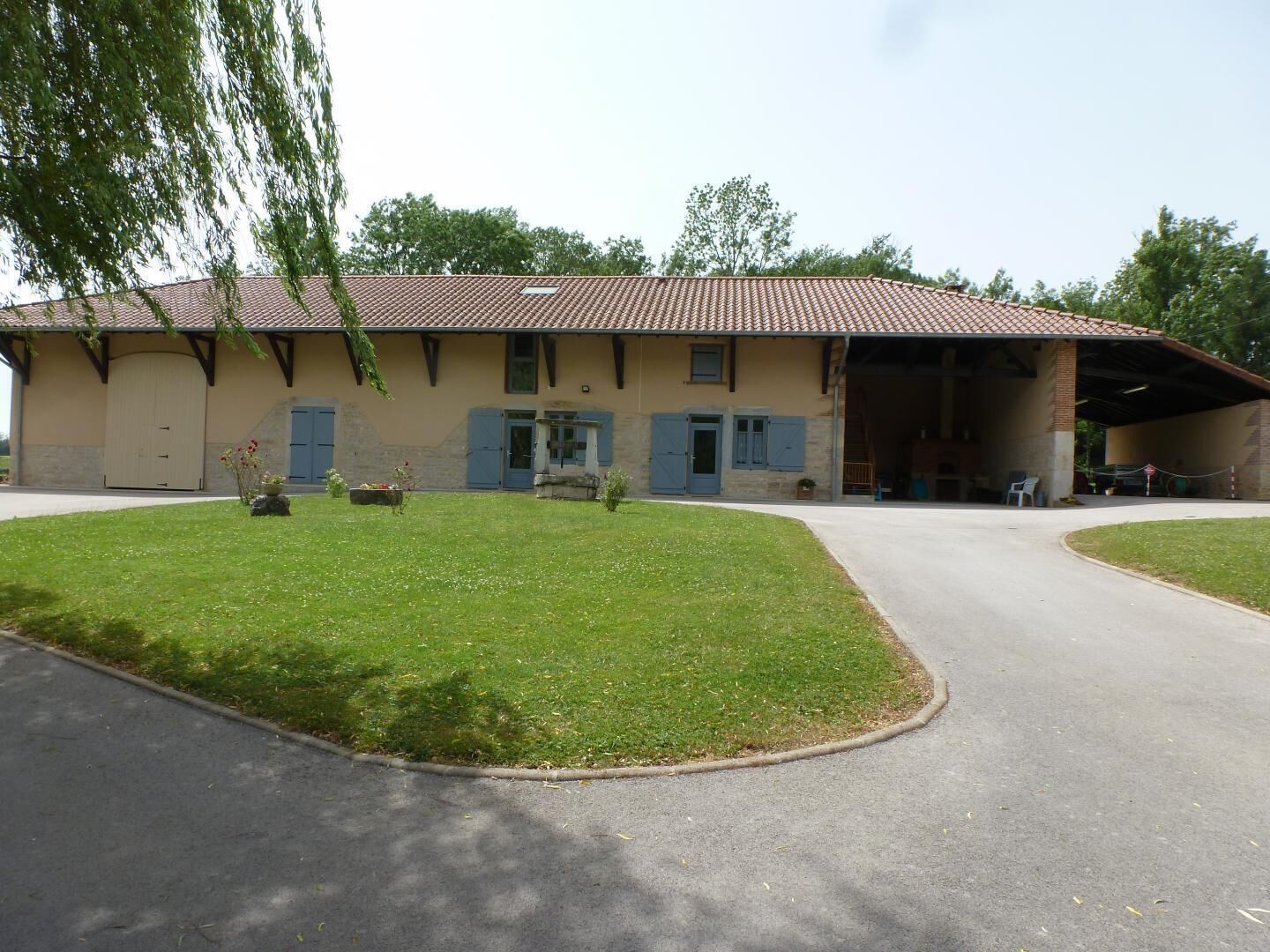 Een gebouw met twee verdiepingen, een pannendak, een overdekte garage en een verzorgd gazon.