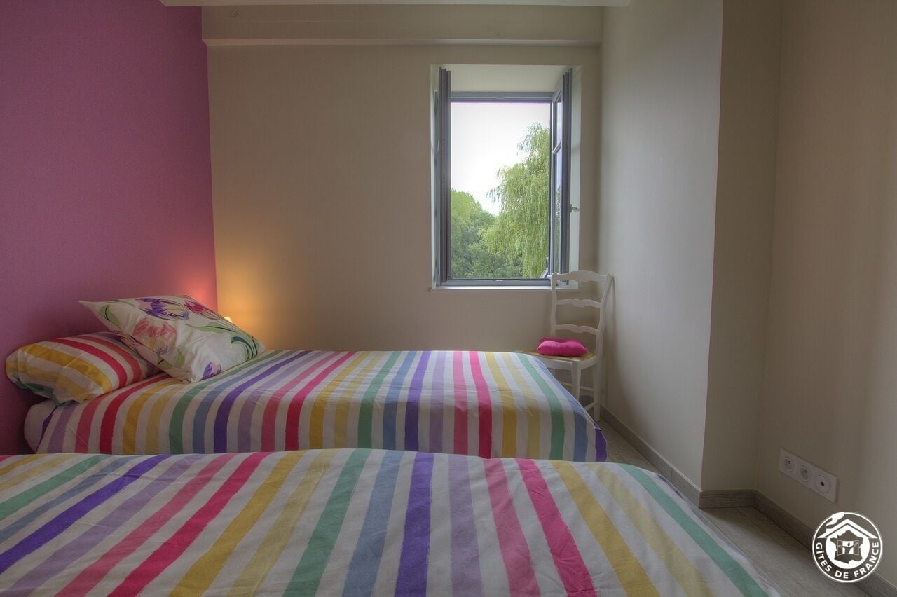 Ein Schlafzimmer mit zwei Betten, einem Fenster und einem Sessel.