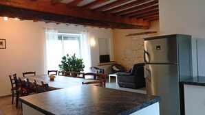 A modern kitchen with a built-in refrigerator, wooden dining table, chairs, and a potted plant.