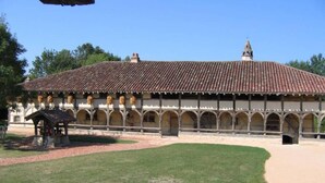 A building with a tiled roof, arched windows, and a central courtyard with a gazebo.
