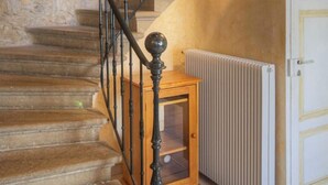 Eine Steintreppe mit schwarzem Metallgeländer, einem Holzschrank und einer weißen Tür.