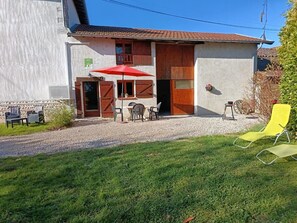 A building with a gravel driveway, a red umbrella, and outdoor seating.
