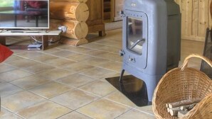 A log cabin interior with a wooden staircase, a fireplace, a television, and a woven basket. - Chalet La Fuste Monts Jura (LELEX)