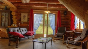 A cozy log cabin interior with a leather sofa, a glass coffee table, and wooden chairs. - Chalet La Fuste Monts Jura (LELEX)