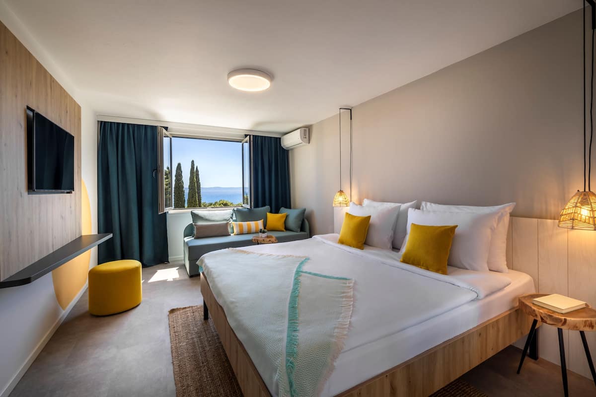 Une chambre d’hôtel moderne avec un grand lit, un canapé, une petite table et un téléviseur.