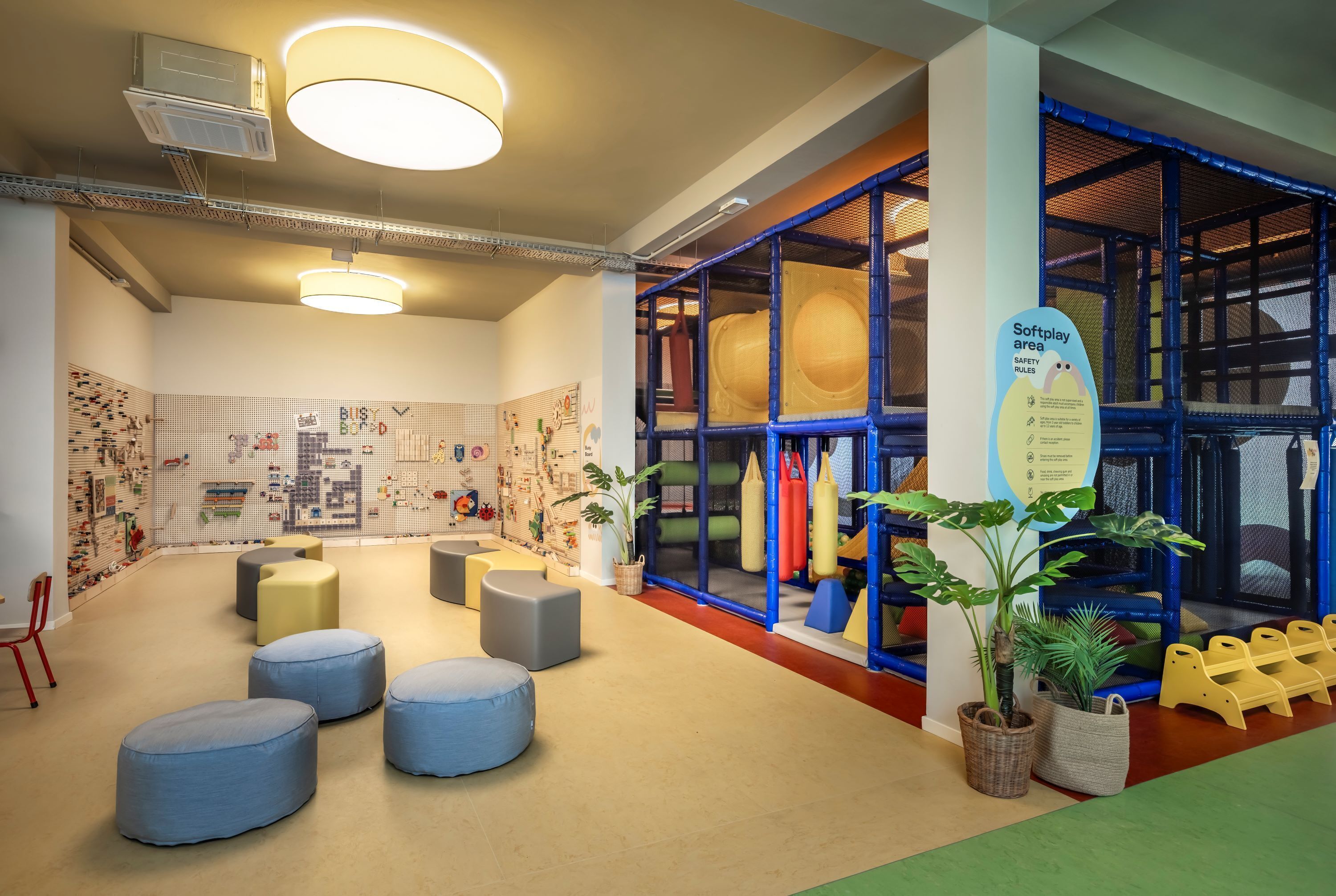 A play area with soft play equipment, seating, and a safety rules sign.