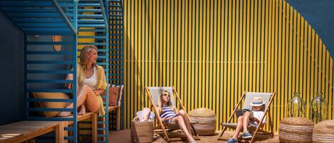 A wooden deck with two lounge chairs, a wooden bench, and a staircase.