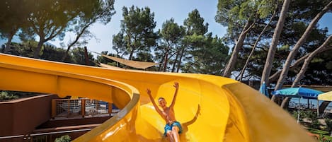 A person sliding down a bright yellow water slide at a water park.