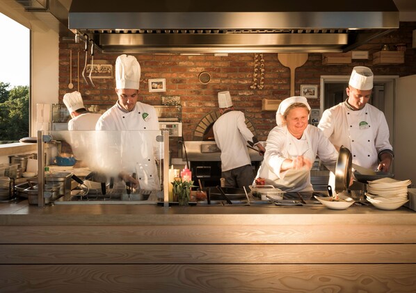 A professional kitchen with chefs preparing food, brick walls, and stainless steel equipment. - Sunny Makarska by Valamar (Makarska)