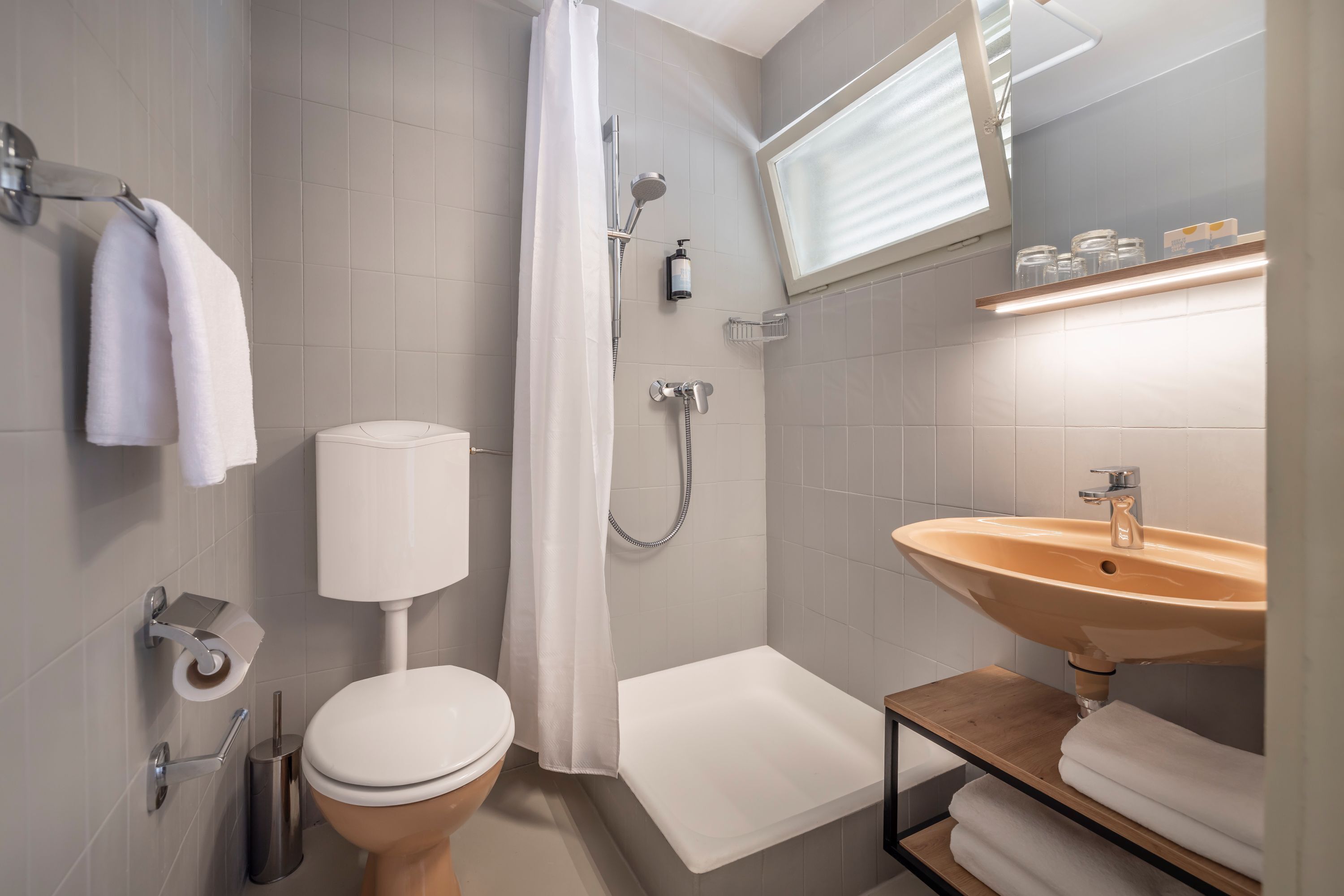 Een moderne badkamer met toilet, douche en wastafel.