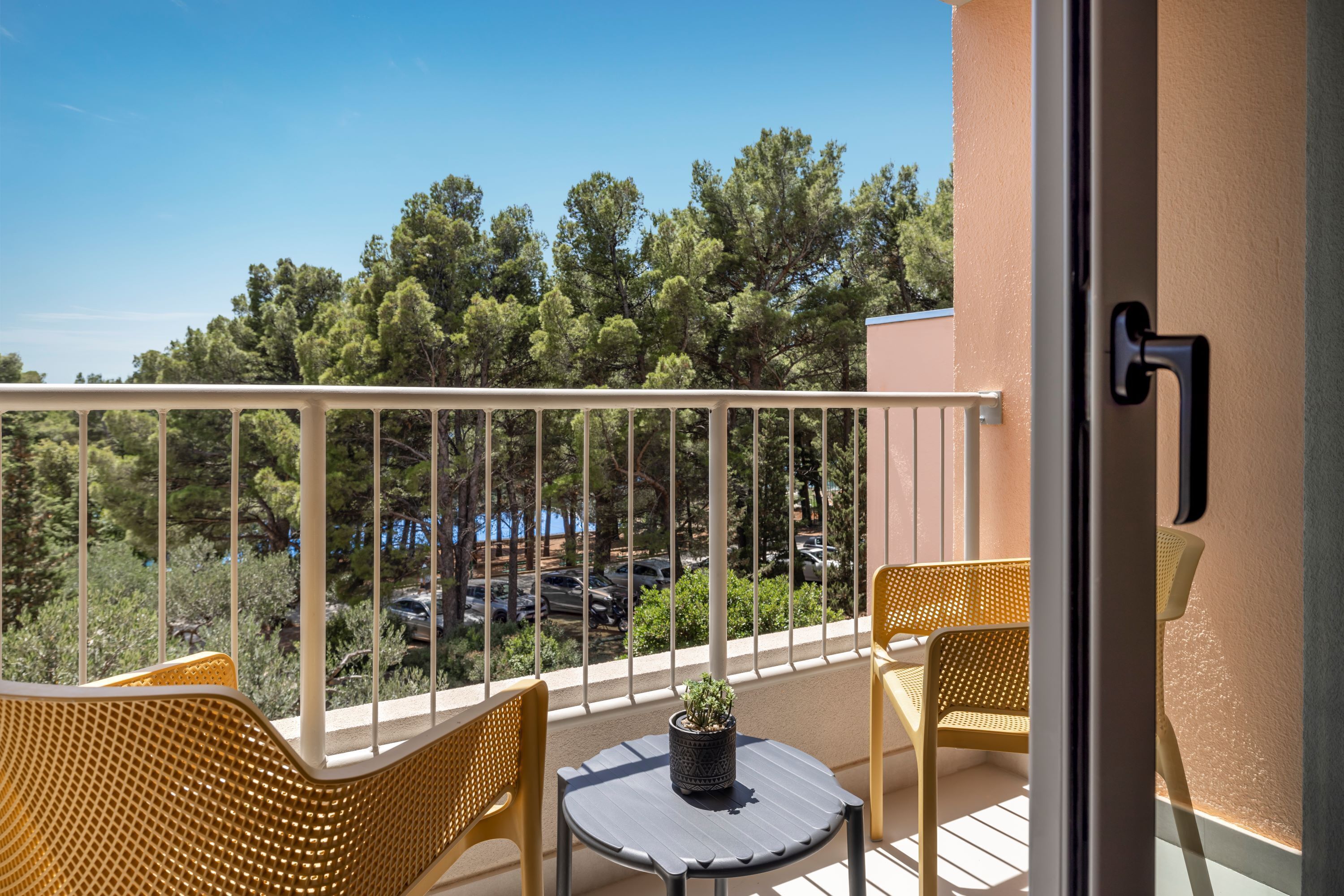 A balcony with two wicker chairs, a small round table, and a potted plant.