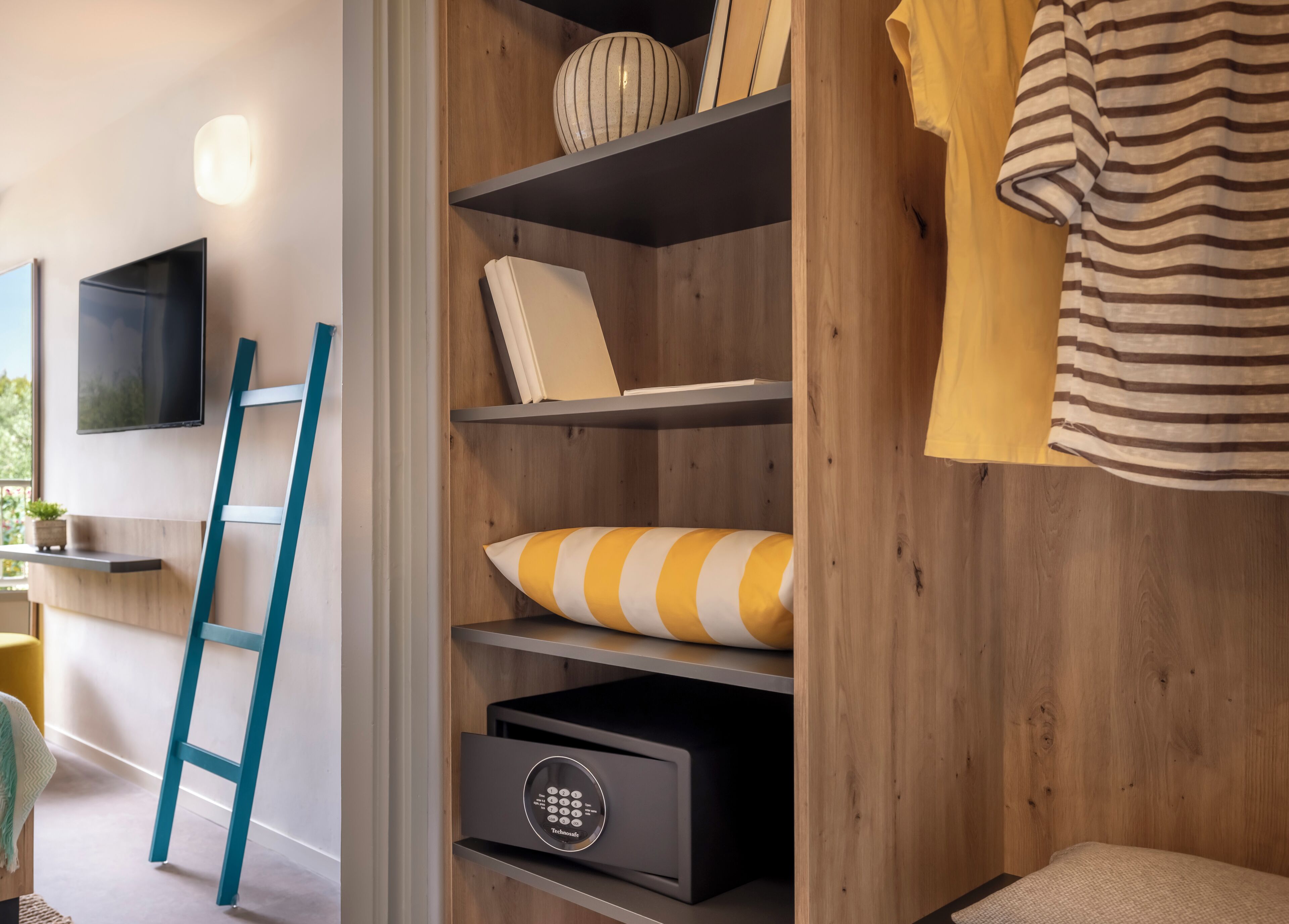 A modern room with a wooden wall, a mounted TV, a ladder, and a built-in storage unit with a lock.