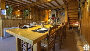 Een houten eetgedeelte met een lange tafel gedekt voor vier personen, omringd door houten stoelen.