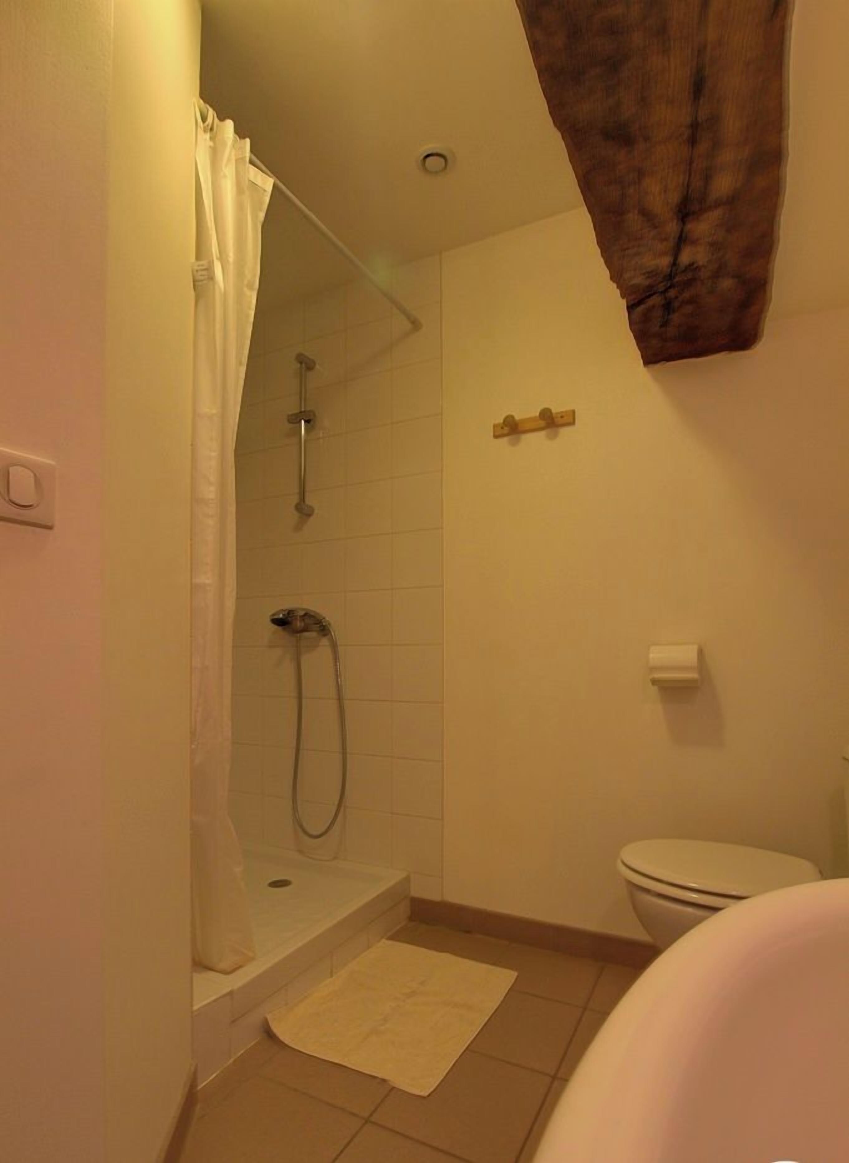 A small bathroom with a shower, toilet, and a white sink.